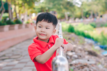 Kid boy sit on the iron balcony,looking the river.の写真素材