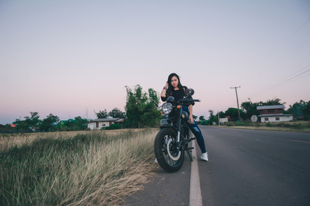 Young sexy woman on a motorcycle in nature on the sunset.Travel Concept.の写真素材