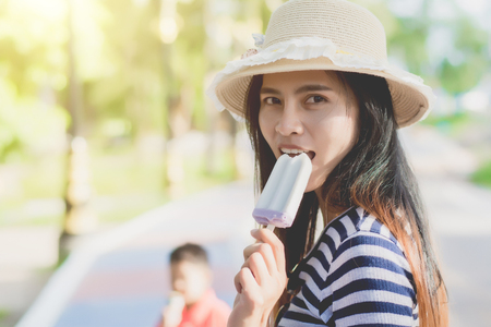 Outdoor closeup fashion portrait of young hipster crazy girl eating ice cream in summer hot weather have fun and good mood.の写真素材
