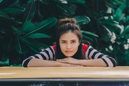 Close up portrait of hipster woman with her yellow car in green background, Hobby concept.の写真素材