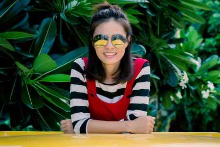 Close up portrait of hipster woman with her yellow car in green background, Hobby concept.の写真素材