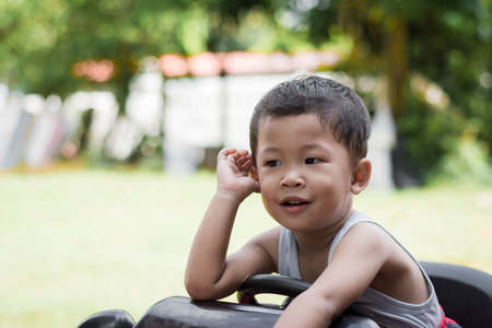 Little boy driving red car with the steering wheel. Little boy driving big toy car and having fun on grass outdoors.の写真素材