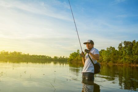Man fishing  in the lake at sunset.の写真素材