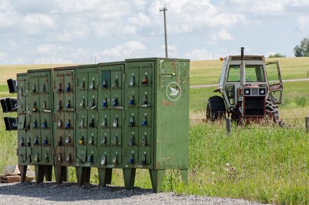 CALGARY, ALBERTA, CANADA, AUGUST 4, 2016: Old rusty locked mailboxes and an abandoned tractor in a...