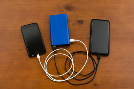 Cellphones recharged sharing a blue power bankの写真素材