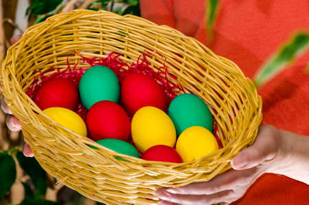 A woman holding a basket with colored easter eggs