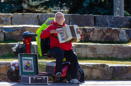 Calgary, Alberta, Canada, October 24, 2021: a senior artist playing accordion in downtown Calgary entertaining people and trying to make a little moneyのeditorial素材