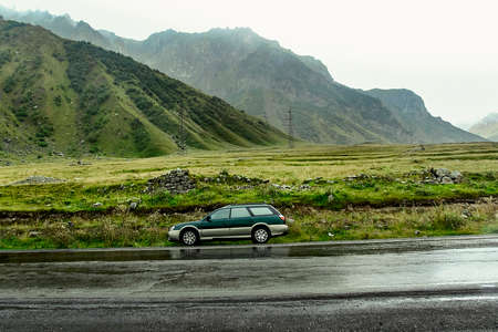 Green wagon Subaru Outback BH stopped on a mountain road