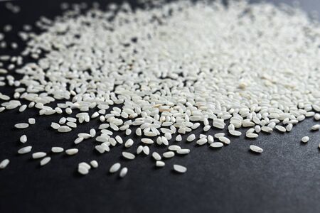 a lot of white long grain rice for pilaf or porridge on black paperの写真素材