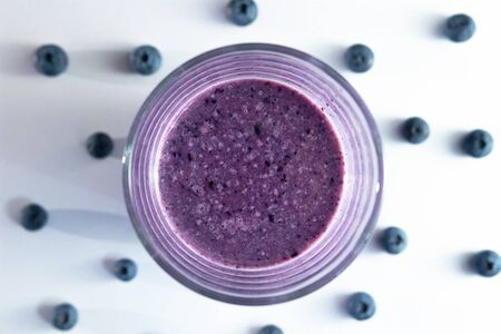 banana and blueberry smoothie in a glass cup on a white background with blueberriesの写真素材