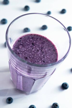 banana and blueberry smoothie in a glass cup on a white background with blueberriesの写真素材