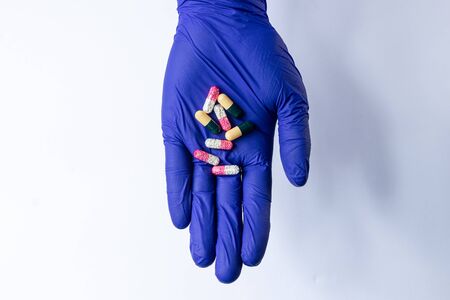 hand with different capsules and tablets of drugs for the treatment of the virus and diseases