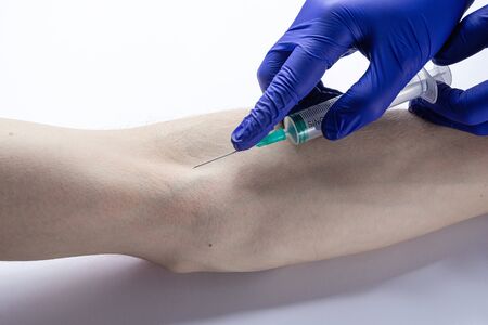 the doctor takes a blood test from a vein with a syringe from a patient
