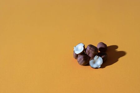 a bunch of peeled hazelnuts on an orange colored background; photo with hard lightの写真素材