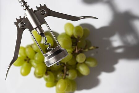 green grapes, cork and corkscrew on a white background; studio photography with soft lightの写真素材