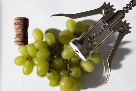 green grapes, cork and corkscrew on a white background; studio photography with soft lightの写真素材