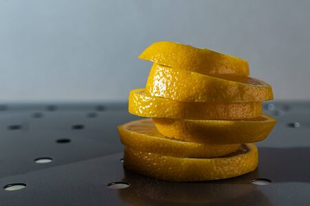 yellow juicy lemon wedges on a metal surface with hard light on a gray backgroundの写真素材
