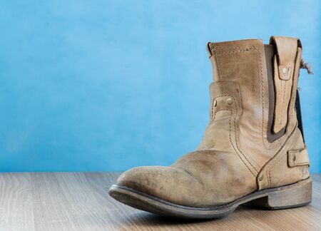 Patina Engineer Leather Boot on wooden surface and blue background with space for text