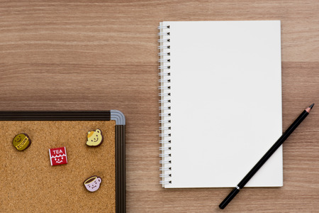 Opened blank ring spiral binding notebook with a pencil and cork board with cute push pins of tea break concept on wooden surface, writing concept, your own contents, space for textの写真素材