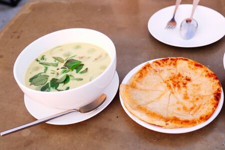 green curry chicken with roti on white dishの写真素材