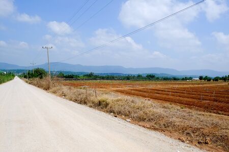 rural road with desolate field and blue skyの写真素材