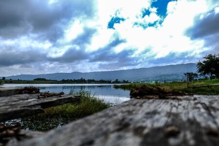 wood pier foreground with lake mountain and sky backgroundの写真素材