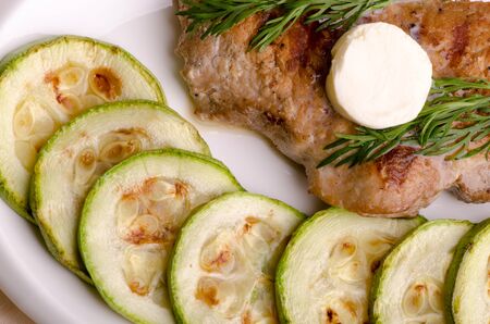 Pork steak, grilled, with melting butter and zucchini, top viewの写真素材