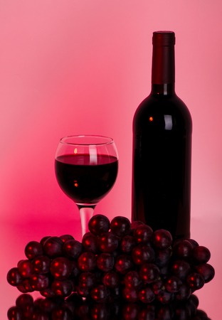 bottle of wine and grapes on a red backgroundの写真素材