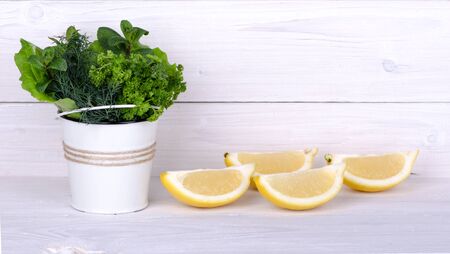 Fresh herbs in a bucket with lemon on a light wooden backgroundの写真素材