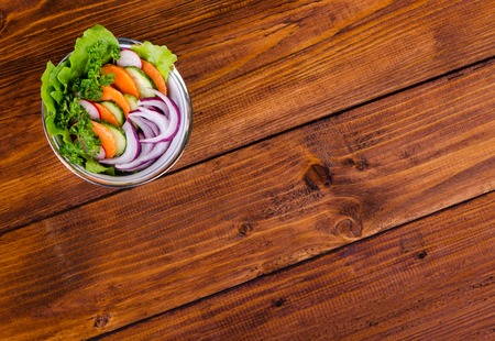 Fresh vegetable salad in a bowl with oriental pattern on the wooden table, top viewの写真素材