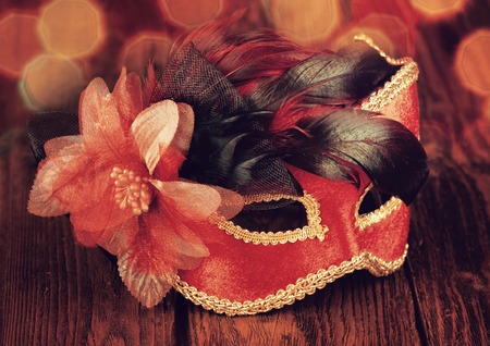 Carnival mask on an old wooden table, toned in redの写真素材