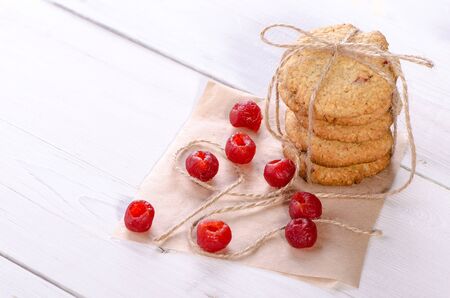 Oatmeal cookies, tied with twine, with a cherry on a wooden table. Healthy dessertの写真素材