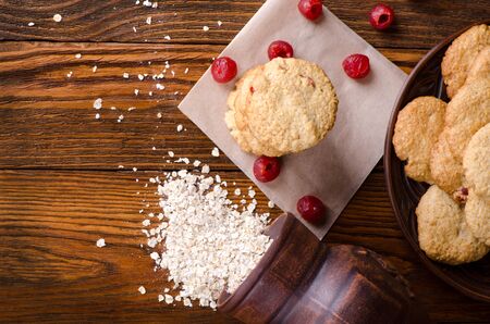 Oatmeal cookies with flakes and cherries on a wooden table. Healthy dessert.の写真素材