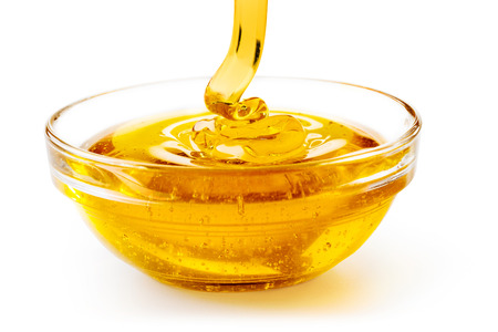 close up of honey dropping into a glass bowl isolated on white backgroundの写真素材