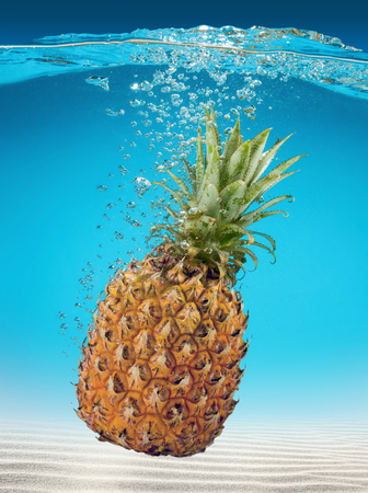 ripe pineapple falling into sea waterの写真素材