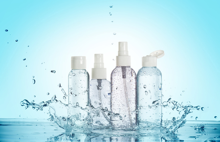 bottles of beauty products in a water splash isolated on blue backgroundの写真素材