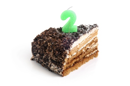 Slice of chocolate birthday cake with number two candle on a white backgroundの写真素材