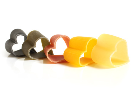 Heart-shaped colored Italian pasta on white backgroundの写真素材