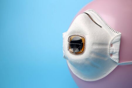Pink balloon with filtering half mask with exhalation valve on blue background