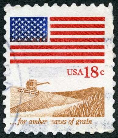 USA - CIRCA 1981: A stamp printed in the USA shows an American Flag, Wheat Fields and harvester, for amber waves of grain, circa 1981のeditorial素材