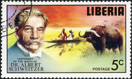 LIBERIA - CIRCA 1975: A stamp printed in Liberia shows Water buffalo egret, man and woman paddling canoe, series Dr. Albert Schweitzer (1875-1965), medical missionary, 100th anniversary of the birth, circa 1975のeditorial素材