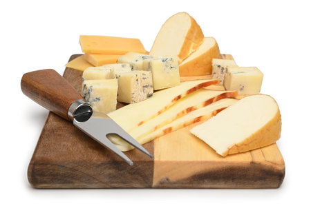 Variety of cheeses with cheese forkon a wooden board on white backgroundの写真素材