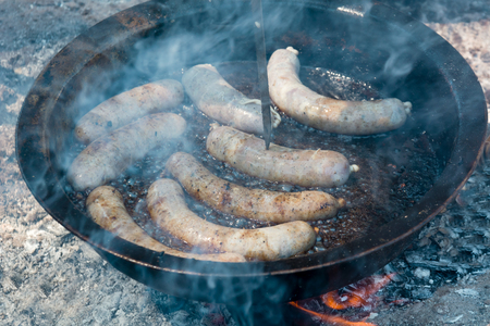 frying sausages in a frying pan on the fireの写真素材
