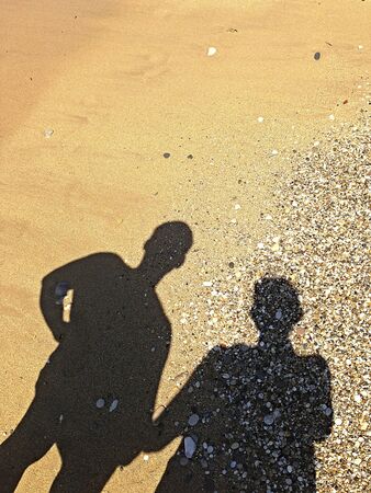 two shadows on the sand on the shore