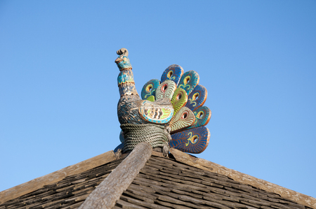 Figurine of a rooster on a tree stump on a background of blue sky.
 Figures of animals made of wood. Woodcarvingの写真素材