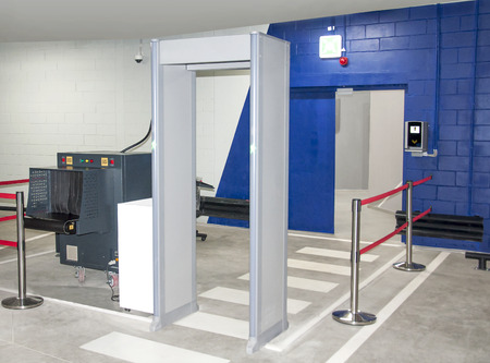 Security checks the metal detector against the background of scanning frames.