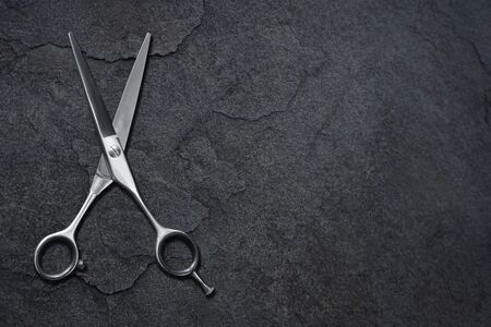 hairdressing different scissors isolated on dark stone background. 