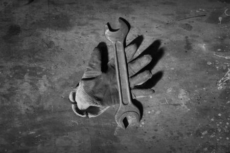 work glove with a spanner on a wooden tableの写真素材