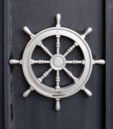A steel ship wheel on a black background. Marine decorations on the wallの写真素材