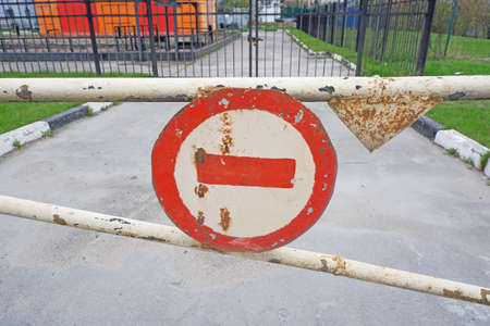 Old rusty gate in the City with weathered stop sign.